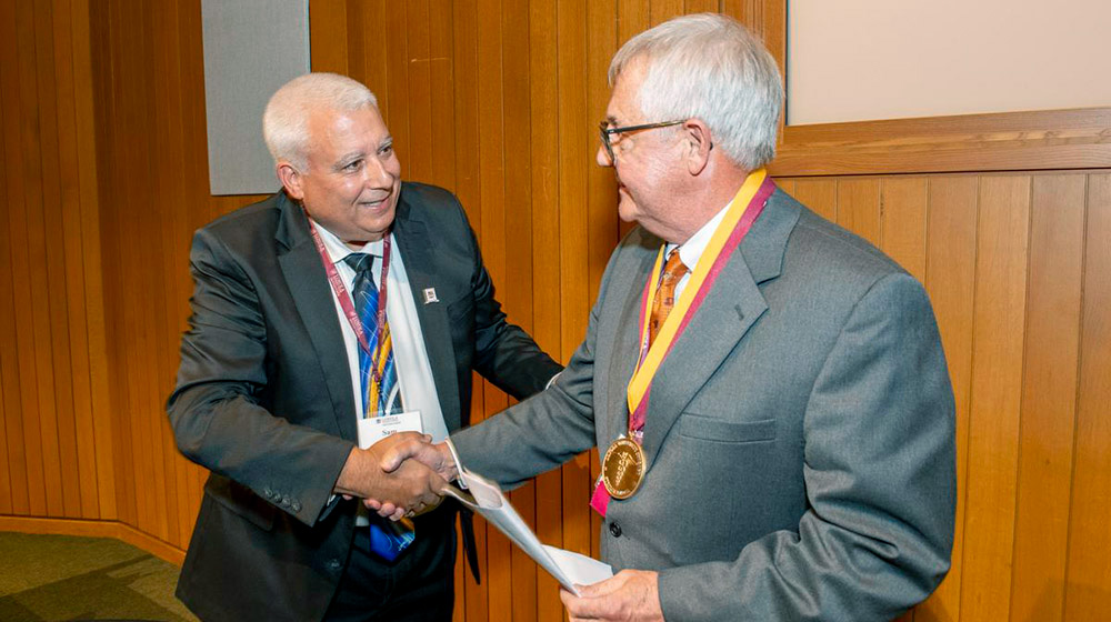 Dean Marzo shaking hands with Dr. Potkul after presenting Dr. Potkul with the Stritch Medal, which h
